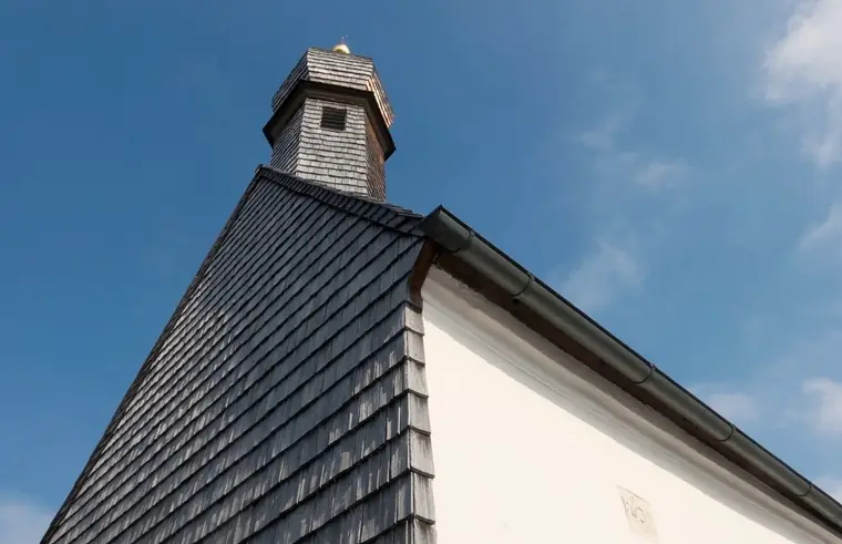 A steep shingle-clad roof with a small tower